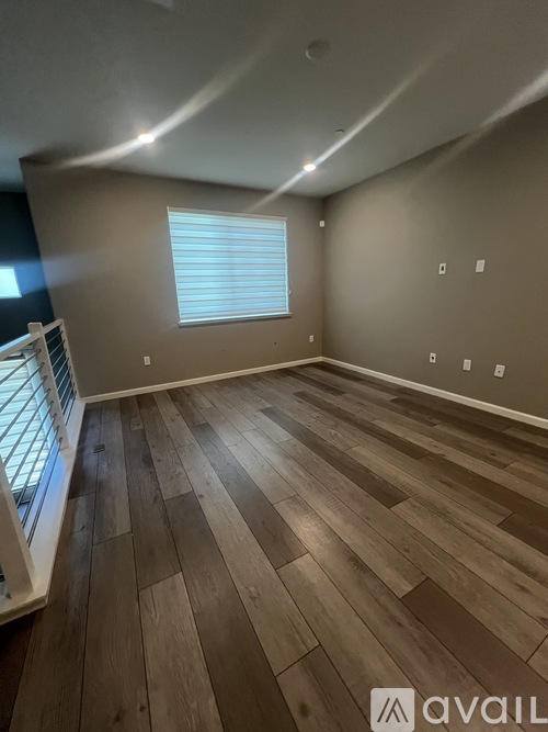 A room with wooden flooring and a window with blinds.