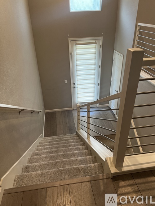 A staircase with a carpeted runner and wooden handrail.