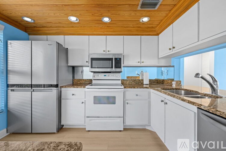 A kitchen with white cabinets and a wooden ceiling.