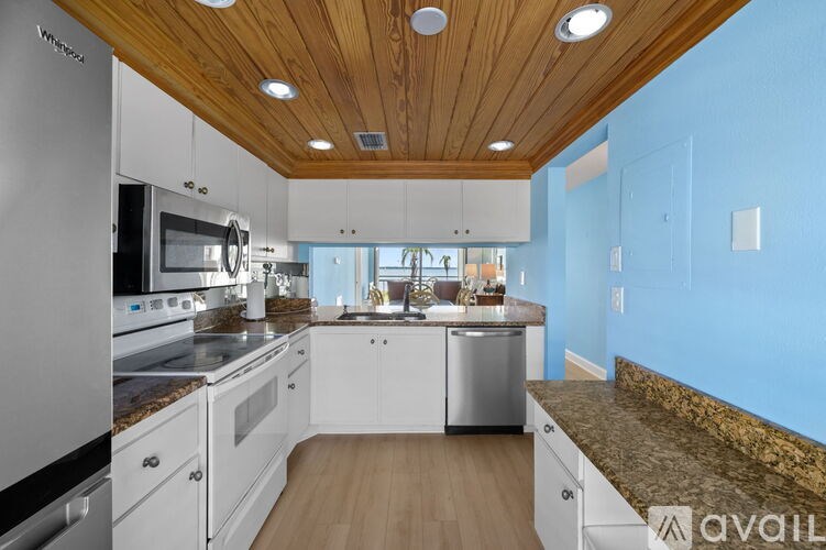 A kitchen with wooden ceiling and white cabinets.