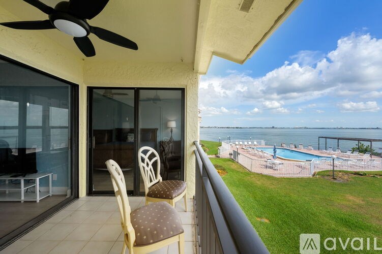 A balcony with a chair and a table overlooking a pool.
