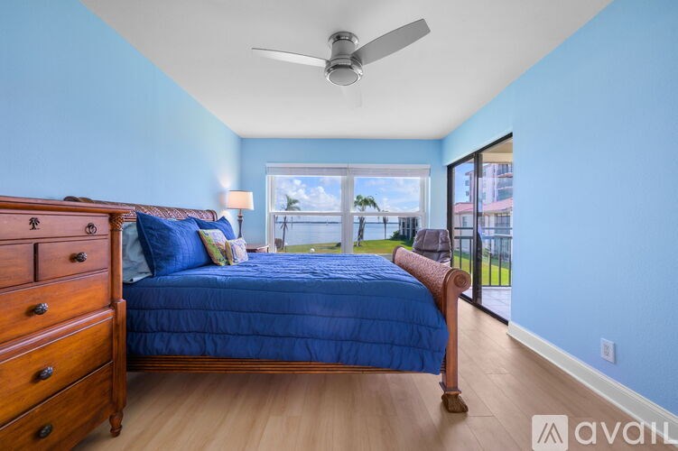 A bedroom with a bed, dresser, and window overlooking a balcony.