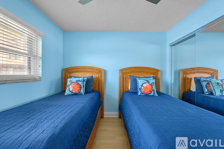 Two twin beds with blue bedspreads and pillows in a room.
