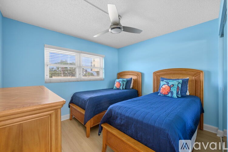 A bedroom with two beds and a ceiling fan.