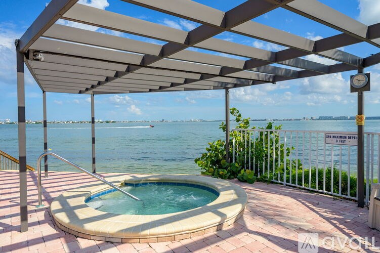 A hot tub is surrounded by a metal fence and a metal pergola.