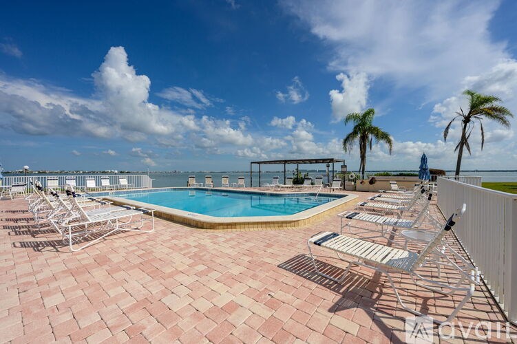 A pool area with sun loungers and palm trees.