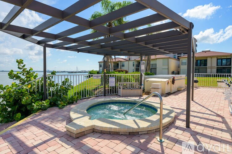 A hot tub is surrounded by a brick patio and a pergola.
