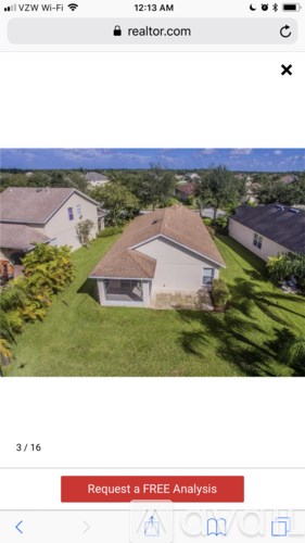 A house with a brown roof is surrounded by greenery.