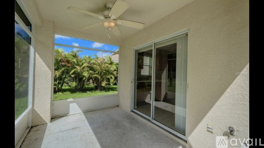 A patio with a ceiling fan and sliding glass doors.