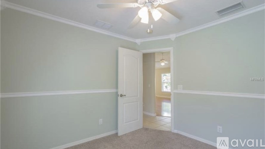 A room with a ceiling fan and a door leading to another room.