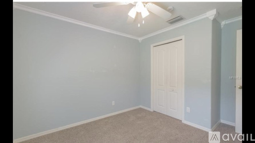 A room with a white door and a ceiling fan.