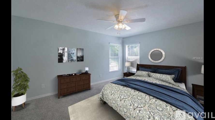 A bedroom with a bed, dresser, and ceiling fan.