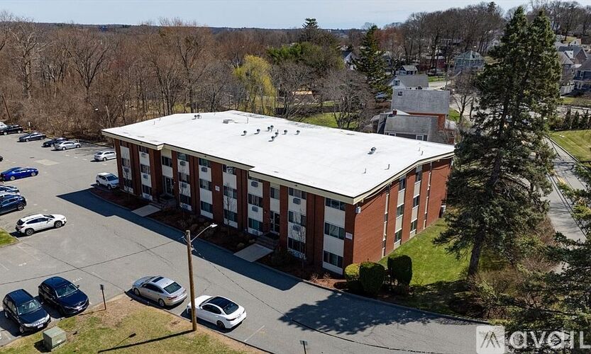 A parking lot with cars and a building with a white roof.