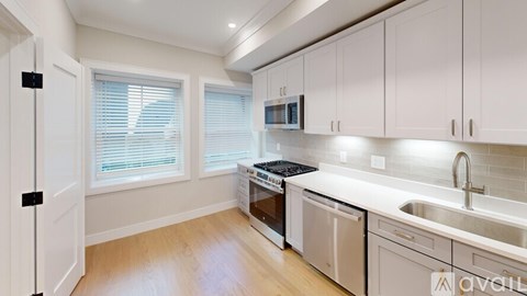 A kitchen with white cabinets and a wooden floor.