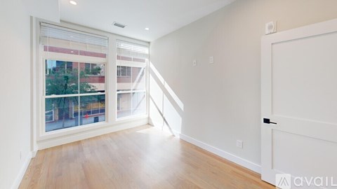 A room with a white door and a window with a view of a building outside.