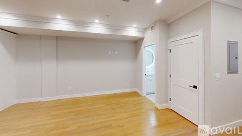 A spacious room with wooden flooring and white walls.