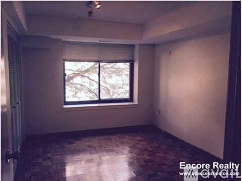 A room with a window and wooden flooring.