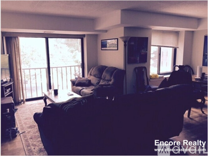 A living room with a couch, chairs, and a television.