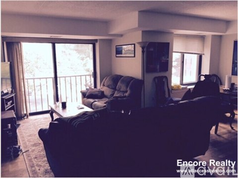 A living room with a couch, chairs, and a television.
