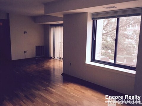 A room with wooden floors and a window showing a view of a street.