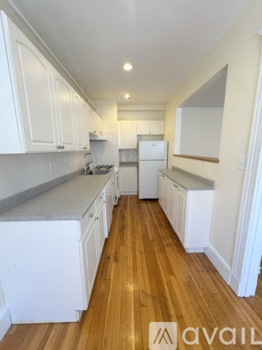 A kitchen with white cabinets and a wooden floor.
