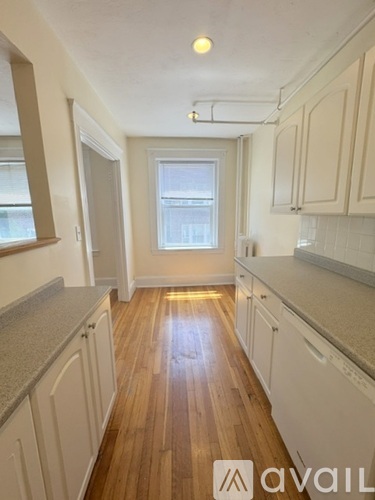 A kitchen with wooden floors and white cabinets.
