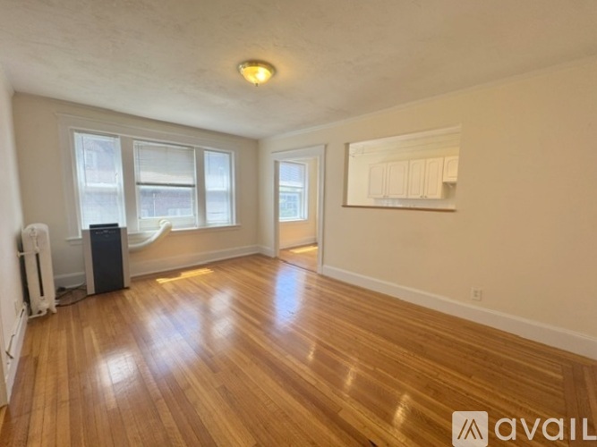 A room with wooden floors and a window with a plant beside it.