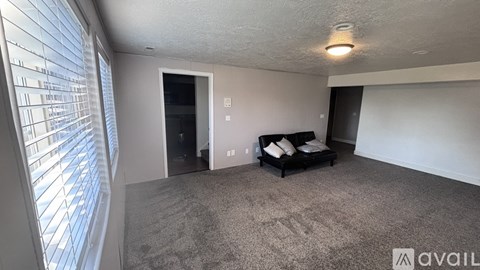 A living room with a couch and a window with blinds.