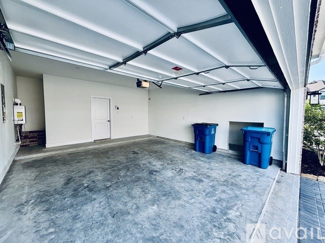 A spacious garage with a concrete floor and two blue bins.