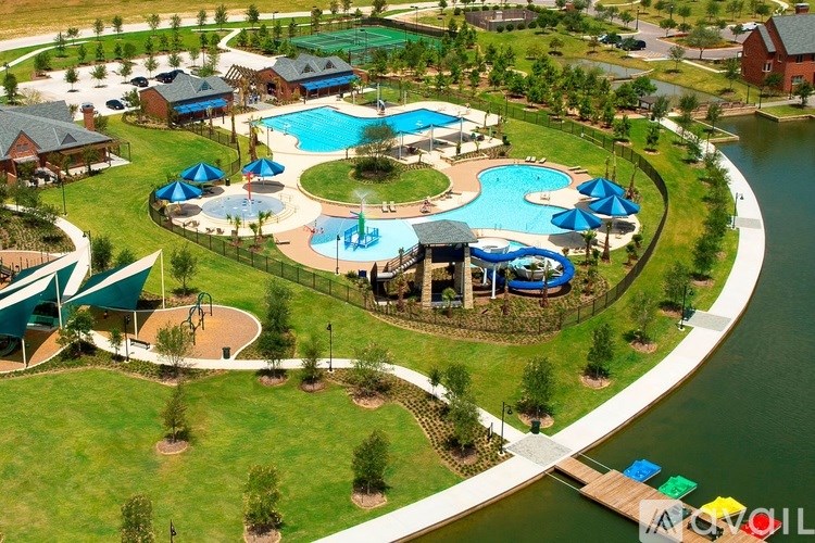 A large outdoor swimming pool surrounded by a grassy area and a fence.