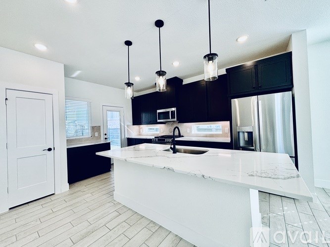 A modern kitchen with a white countertop and black cabinets.