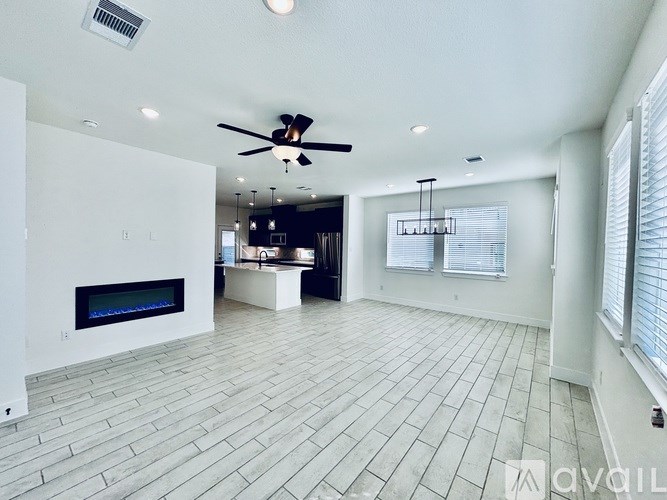 A spacious living room with a fireplace and a ceiling fan.