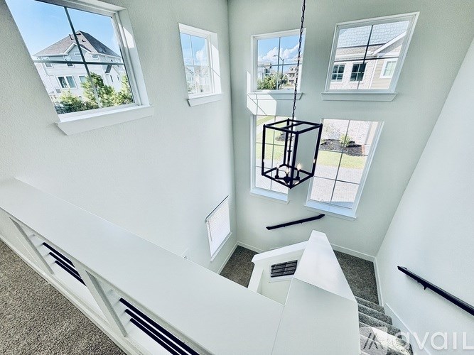 A white staircase with a black railing and a hanging light fixture.