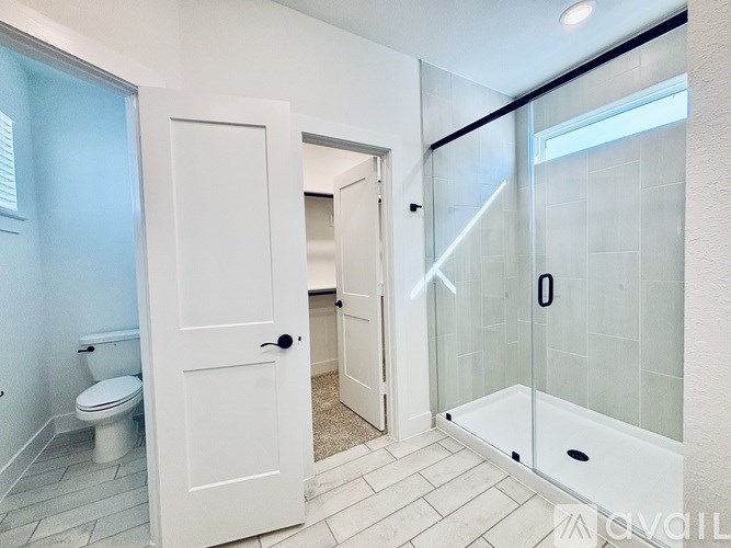 A white door is open to a bathroom with a toilet and a walk-in shower.