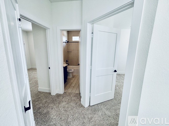 A white door is open to a bathroom with a toilet and sink.
