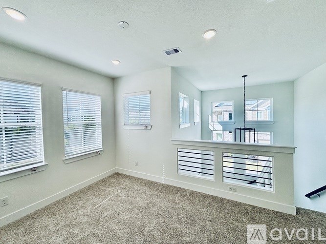A room with a carpet floor, a window with blinds, and a ceiling with lights.