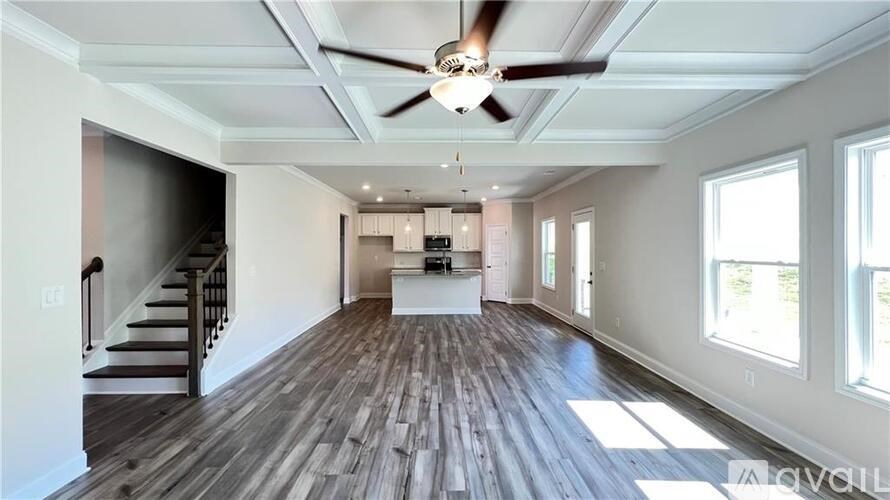 A spacious room with wooden floors and a ceiling fan.