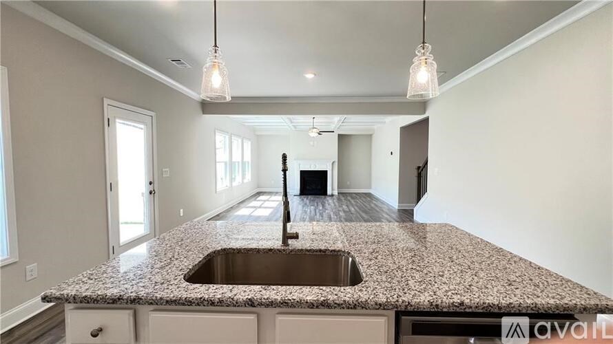 A kitchen with granite countertops and pendant lights.