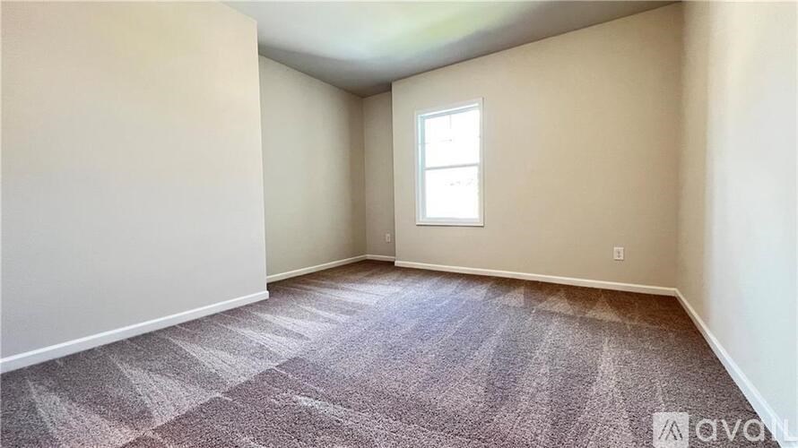 A room with a carpeted floor and a window.