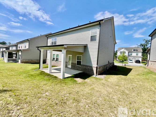 A house with a grey siding and a white trim is surrounded by other houses.