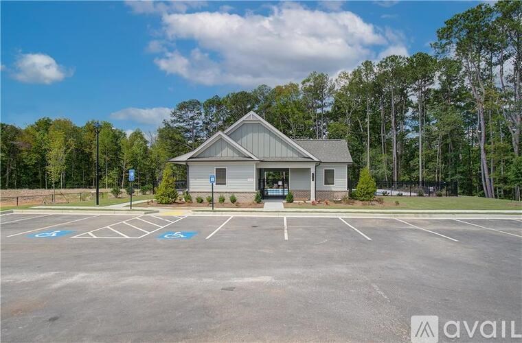 A parking lot with a building and trees in the background.