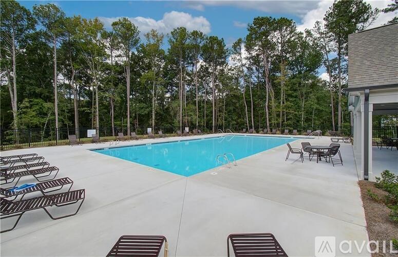A large outdoor swimming pool surrounded by trees and lounge chairs.