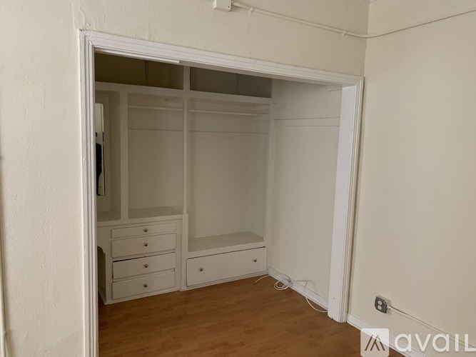A room with a white wardrobe and drawers.