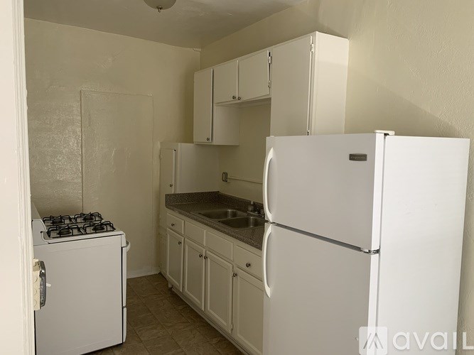 A small kitchen with a white fridge, stove and cabinets.