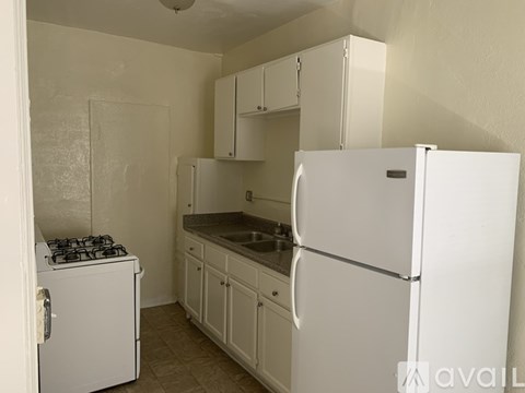 A small kitchen with a white fridge, stove and cabinets.