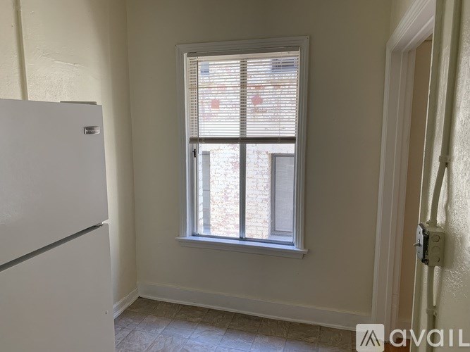 A white refrigerator is in a room with a window.