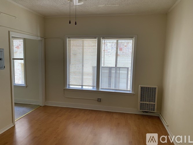 A room with wooden floors and a window with blinds.