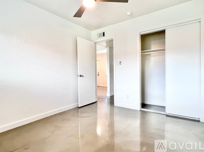A spacious room with a white door and a ceiling fan.