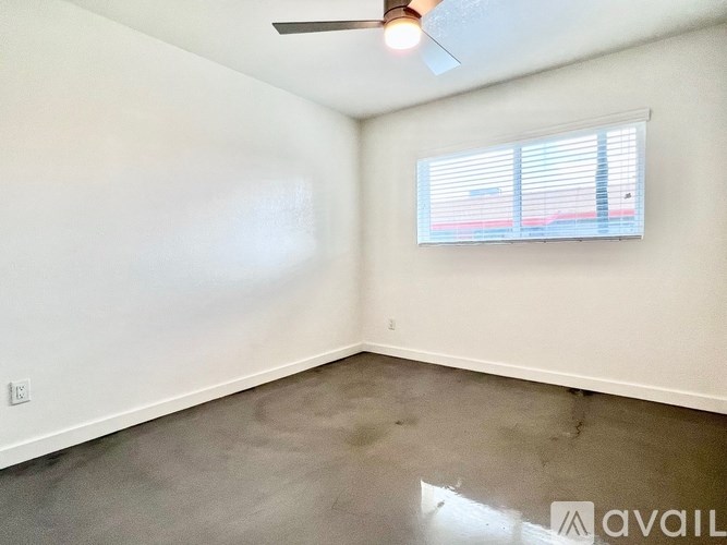 A room with a ceiling fan and a window with blinds.