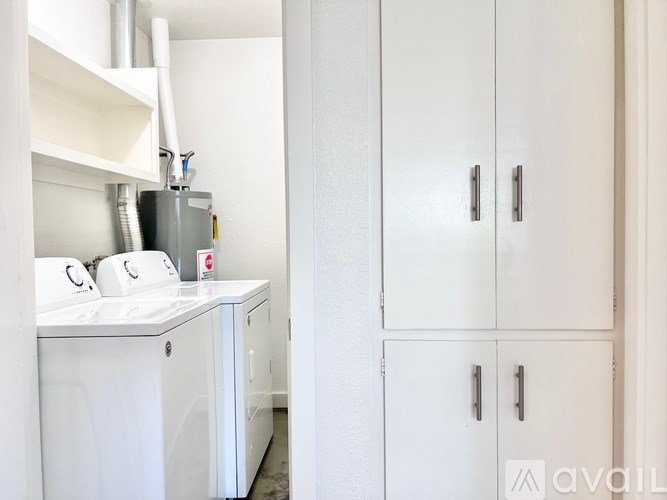 A white kitchen with a washing machine and a cabinet.